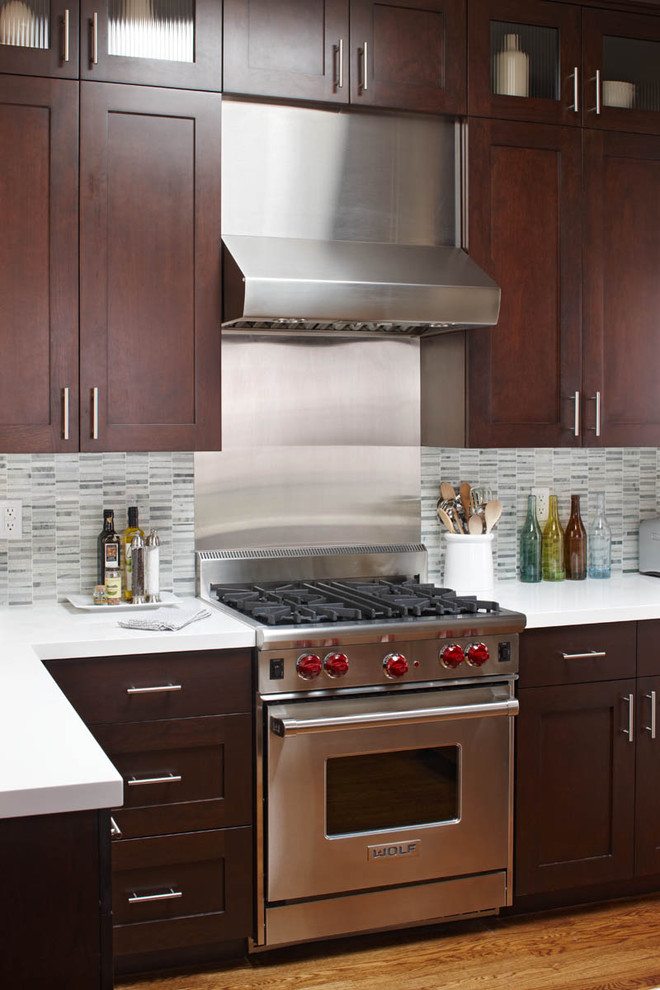 This is an example of a contemporary kitchen in San Francisco with shaker cabinets, stainless steel appliances, dark wood cabinets, white splashback, stone tiled splashback and engineered stone countertops.