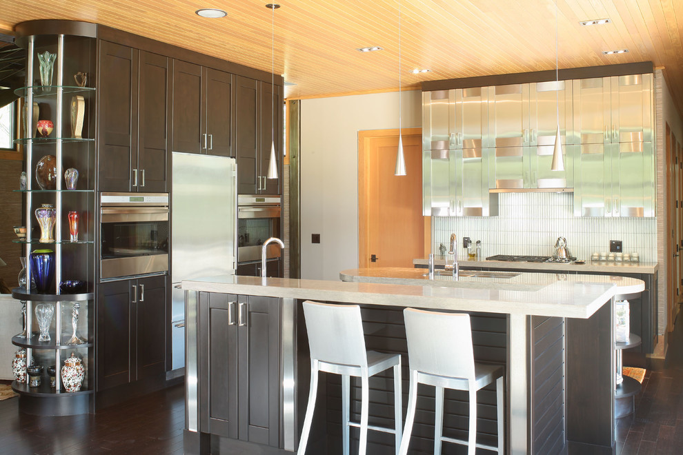 Diseño de cocina actual con armarios estilo shaker, puertas de armario en acero inoxidable, salpicadero blanco y electrodomésticos de acero inoxidable