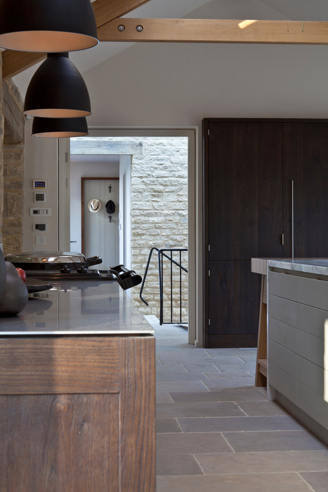 Aménagement d'une grande cuisine ouverte parallèle contemporaine en bois foncé avec plan de travail en marbre, un sol en calcaire, îlot, un évier intégré et un électroménager noir.