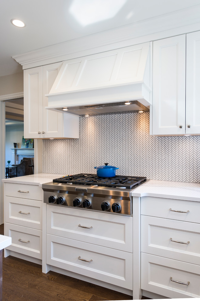 Large transitional u-shaped medium tone wood floor and brown floor eat-in kitchen photo in Vancouver with an undermount sink, recessed-panel cabinets, white cabinets, quartz countertops, white backsplash, mosaic tile backsplash, stainless steel appliances and an island