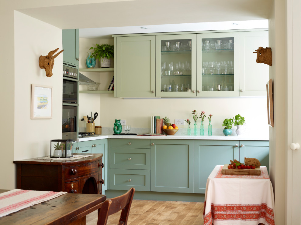 Design ideas for a medium sized traditional l-shaped kitchen/diner in Other with shaker cabinets, green cabinets, medium hardwood flooring, no island, beige floors and white worktops.
