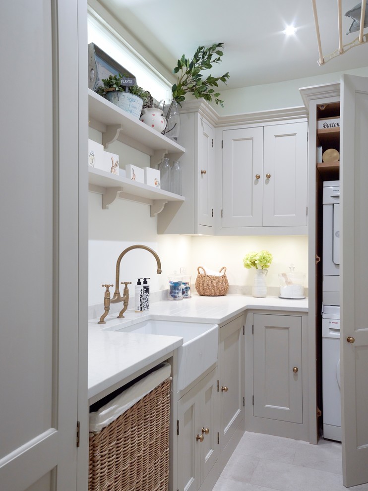 Inspiration for a medium sized classic l-shaped kitchen/diner in London with a belfast sink, shaker cabinets, white cabinets, quartz worktops, white splashback, metro tiled splashback, stainless steel appliances, light hardwood flooring and an island.