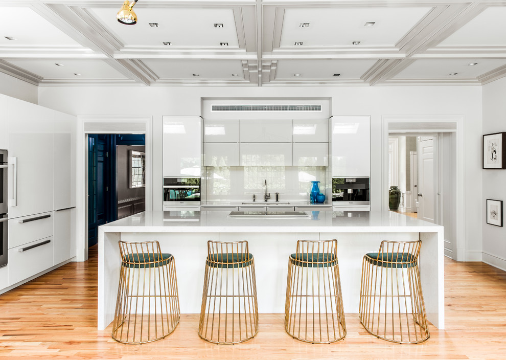 Photo of a contemporary kitchen in Boston with a submerged sink, flat-panel cabinets, white cabinets, white splashback, glass sheet splashback, an island and medium hardwood flooring.
