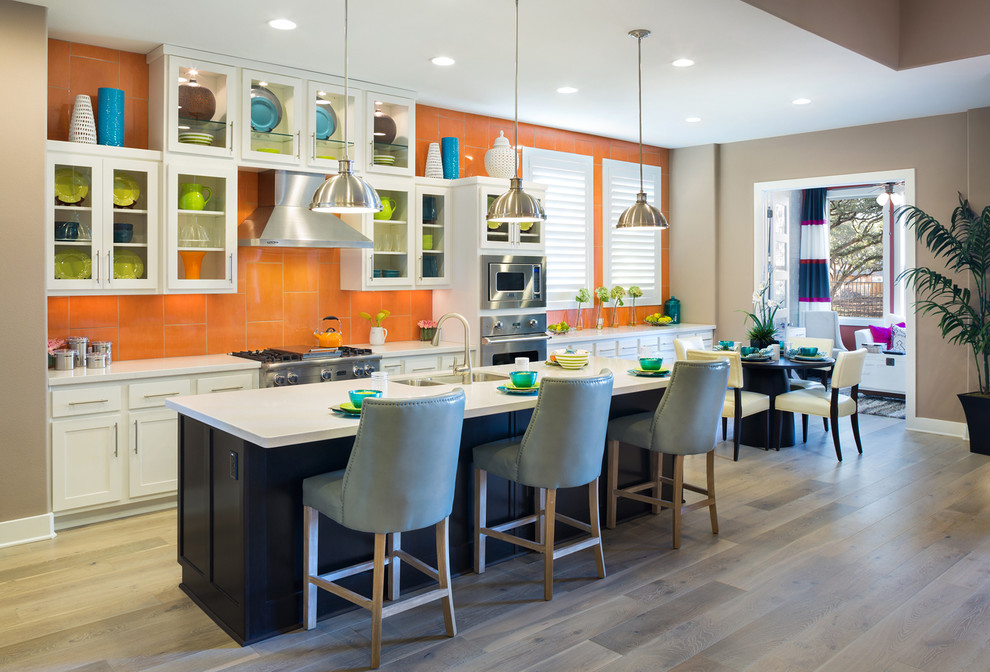 Idéer för ett modernt kök och matrum, med en dubbel diskho, luckor med glaspanel, vita skåp, rostfria vitvaror och orange stänkskydd