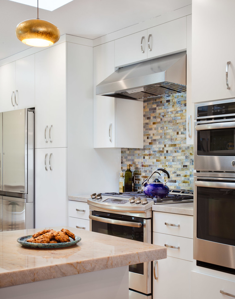 Exempel på ett litet modernt l-kök, med släta luckor, vita skåp, bänkskiva i kvarts, flerfärgad stänkskydd, stänkskydd i mosaik, rostfria vitvaror och en halv köksö