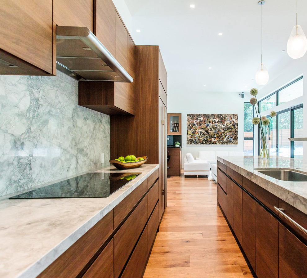 Bild på ett mellanstort funkis kök, med en undermonterad diskho, släta luckor, skåp i mellenmörkt trä, grönt stänkskydd, stänkskydd i sten, rostfria vitvaror, mellanmörkt trägolv, en köksö och brunt golv