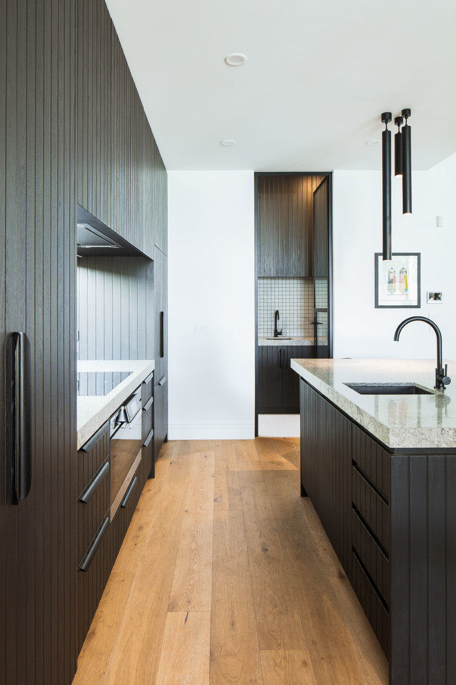 Ejemplo de cocina contemporánea de tamaño medio abierta con puertas de armario negras, encimera de cuarzo compacto, salpicadero de vidrio, electrodomésticos negros, una isla y encimeras grises