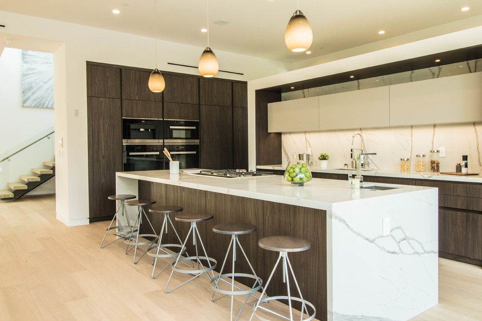 Trendy l-shaped light wood floor and beige floor kitchen photo in Los Angeles with an undermount sink, flat-panel cabinets, dark wood cabinets, white backsplash and an island