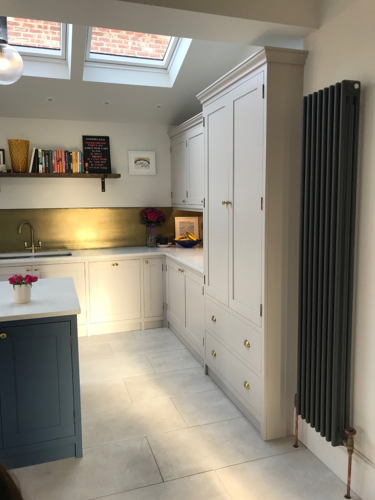 This is an example of a medium sized classic l-shaped kitchen/diner in Manchester with a built-in sink, shaker cabinets, blue cabinets, quartz worktops, metallic splashback, integrated appliances, ceramic flooring, an island, grey floors and white worktops.