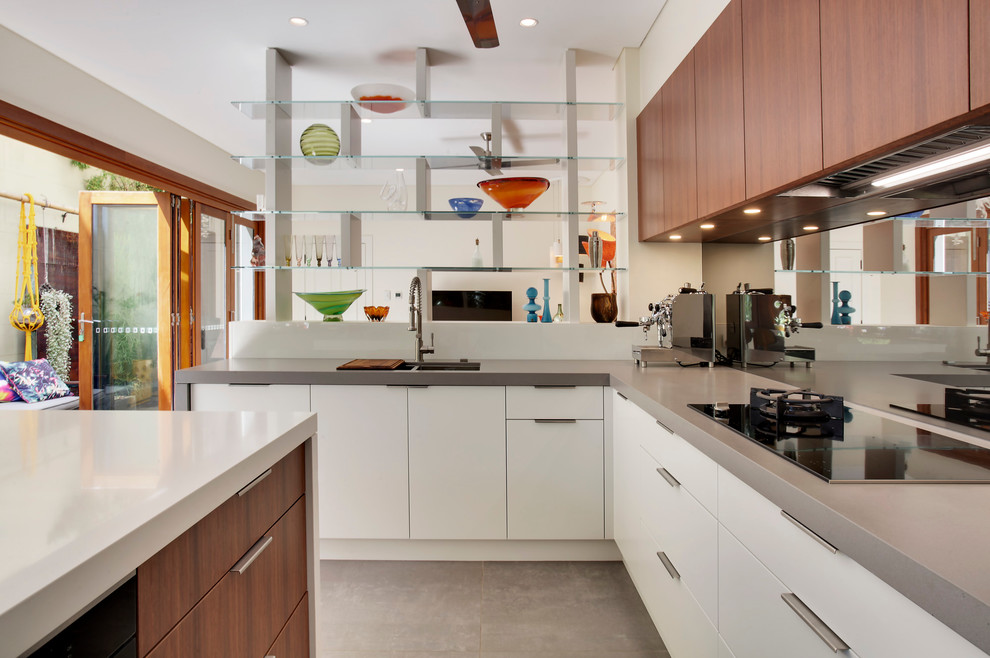 Exempel på ett stort modernt kök, med en undermonterad diskho, släta luckor, vita skåp, bänkskiva i kvarts, grått stänkskydd, spegel som stänkskydd, svarta vitvaror, betonggolv och en köksö