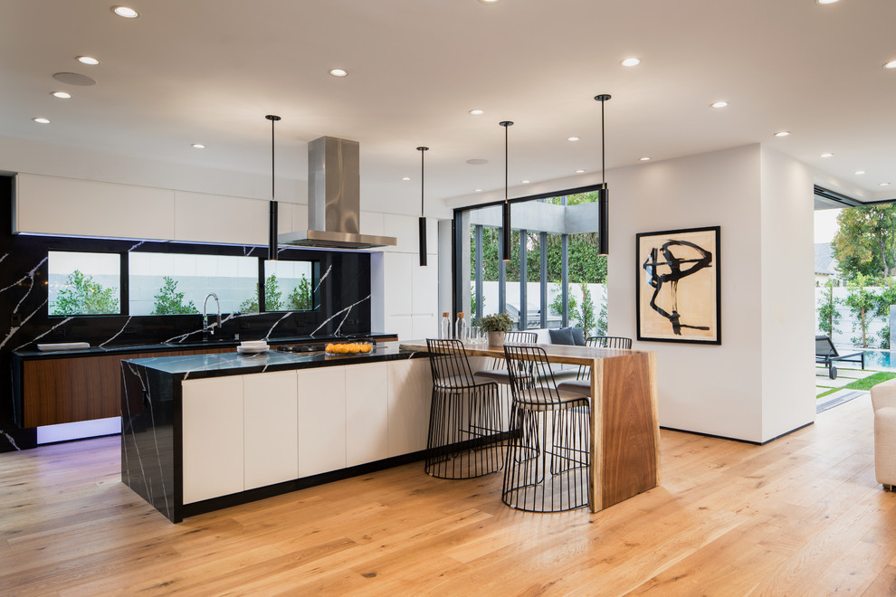 Large trendy l-shaped light wood floor and beige floor open concept kitchen photo in Los Angeles with a drop-in sink, medium tone wood cabinets, granite countertops, black backsplash, stainless steel appliances and an island