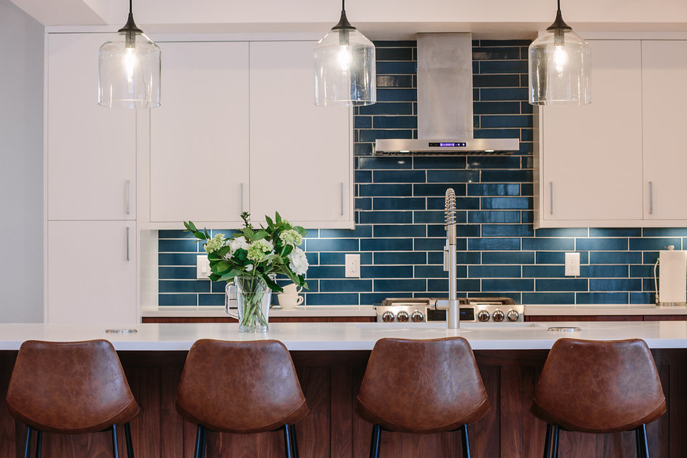 デンバーにある高級な巨大なコンテンポラリースタイルのおしゃれなキッチン (アンダーカウンターシンク、フラットパネル扉のキャビネット、中間色木目調キャビネット、クオーツストーンカウンター、青いキッチンパネル、セラミックタイルのキッチンパネル、シルバーの調理設備、淡色無垢フローリング、茶色い床) の写真