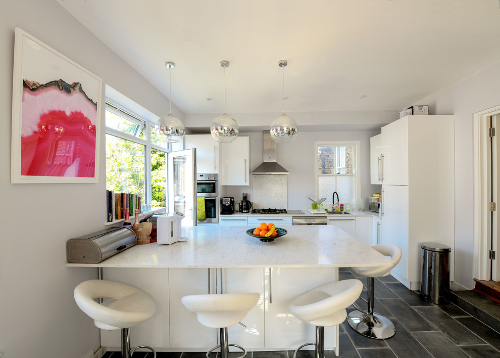 Inspiration for a medium sized contemporary l-shaped kitchen in Surrey with a submerged sink, flat-panel cabinets, white cabinets, white splashback, stainless steel appliances, an island, black floors and white worktops.