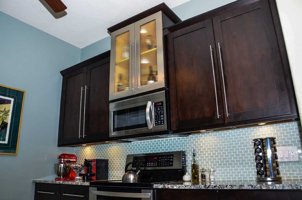 Bild på ett funkis kök och matrum, med luckor med glaspanel, skåp i rostfritt stål, granitbänkskiva och rostfria vitvaror