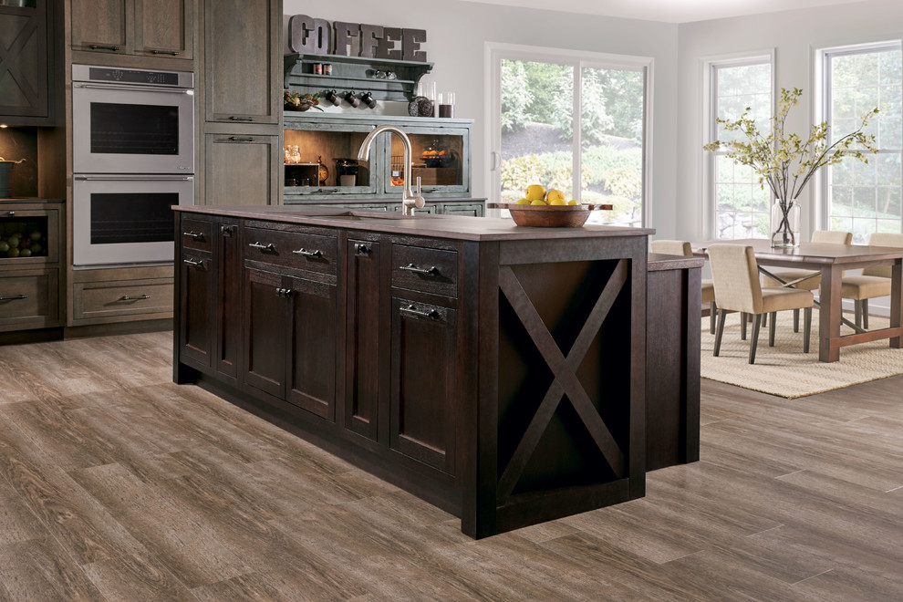 Large elegant l-shaped light wood floor and brown floor eat-in kitchen photo in New York with an undermount sink, shaker cabinets, dark wood cabinets, soapstone countertops, black backsplash, stone slab backsplash, stainless steel appliances and an island