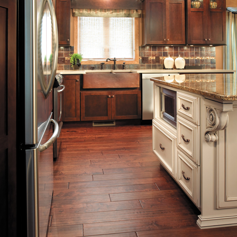 Example of a large classic l-shaped dark wood floor and brown floor open concept kitchen design in Other with a farmhouse sink, recessed-panel cabinets, white cabinets, granite countertops, brown backsplash, stainless steel appliances and an island
