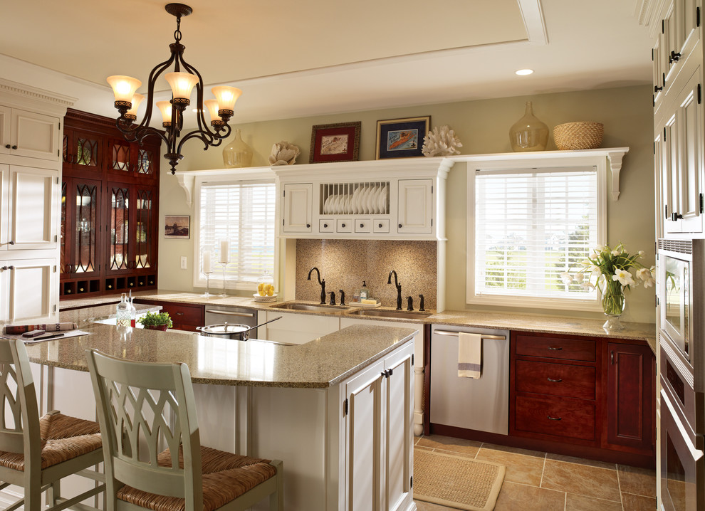 Foto på ett mycket stort vintage kök, med en dubbel diskho, luckor med infälld panel, vita skåp, en köksö, rostfria vitvaror, beige stänkskydd, granitbänkskiva, klinkergolv i porslin och brunt golv