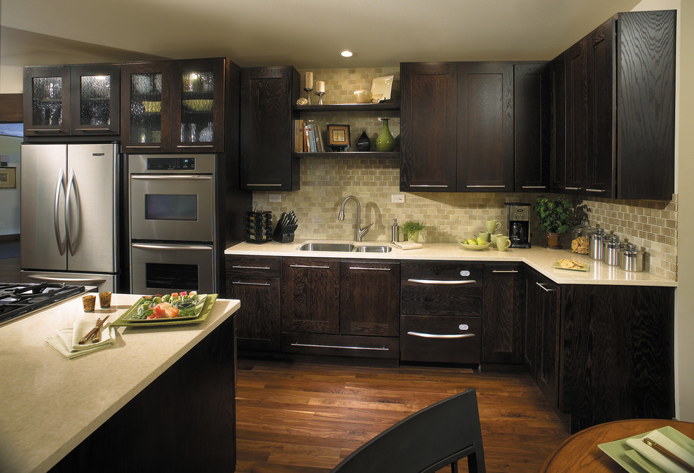 Photo of a large classic l-shaped kitchen/diner in Other with a submerged sink, recessed-panel cabinets, dark wood cabinets, stainless steel appliances, medium hardwood flooring, an island, beige splashback and brown floors.