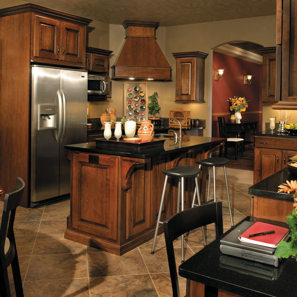 他の地域にある広いトラディショナルスタイルのおしゃれなキッチン (アンダーカウンターシンク、レイズドパネル扉のキャビネット、中間色木目調キャビネット、シルバーの調理設備、ベージュの床) の写真