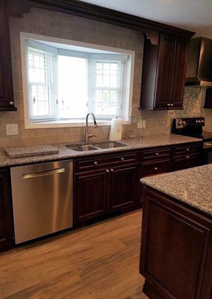 Example of a large classic l-shaped light wood floor and yellow floor kitchen pantry design in Other with an undermount sink, raised-panel cabinets, dark wood cabinets, stainless steel appliances, an island, granite countertops, multicolored backsplash, ceramic backsplash and beige countertops