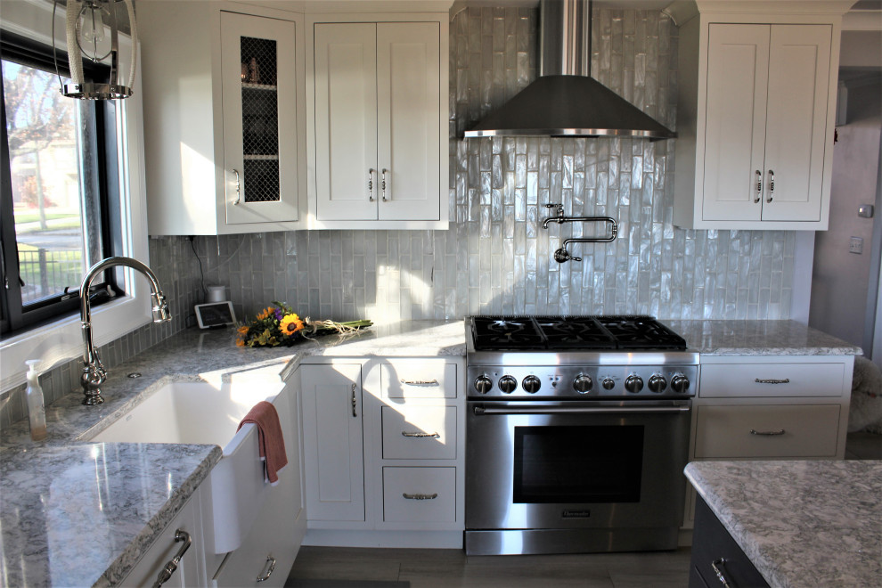 Klassisk inredning av ett stort flerfärgad flerfärgat kök, med en rustik diskho, luckor med infälld panel, vita skåp, bänkskiva i kvarts, vitt stänkskydd, stänkskydd i keramik, integrerade vitvaror, mellanmörkt trägolv, en köksö och brunt golv