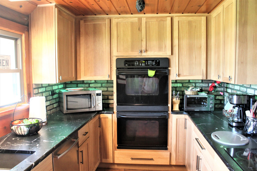 Exempel på ett stort lantligt svart svart kök, med en undermonterad diskho, släta luckor, bänkskiva i täljsten, rött stänkskydd, stänkskydd i tegel, rostfria vitvaror, klinkergolv i porslin, en halv köksö och rött golv