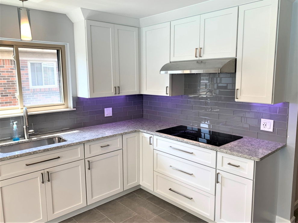 Design ideas for a medium sized traditional l-shaped enclosed kitchen in Detroit with a single-bowl sink, shaker cabinets, white cabinets, engineered stone countertops, grey splashback, glass tiled splashback, integrated appliances, porcelain flooring, grey floors and grey worktops.