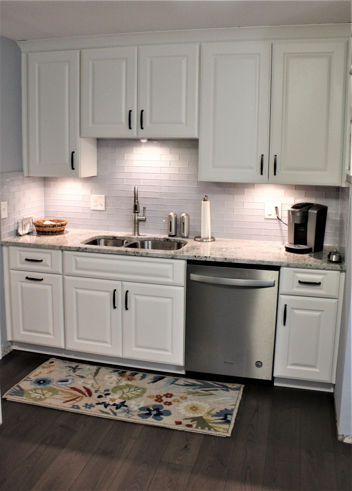 Klassisk inredning av ett avskilt, stort flerfärgad flerfärgat l-kök, med en undermonterad diskho, luckor med upphöjd panel, vita skåp, granitbänkskiva, vitt stänkskydd, stänkskydd i glaskakel, rostfria vitvaror, mörkt trägolv, en halv köksö och brunt golv