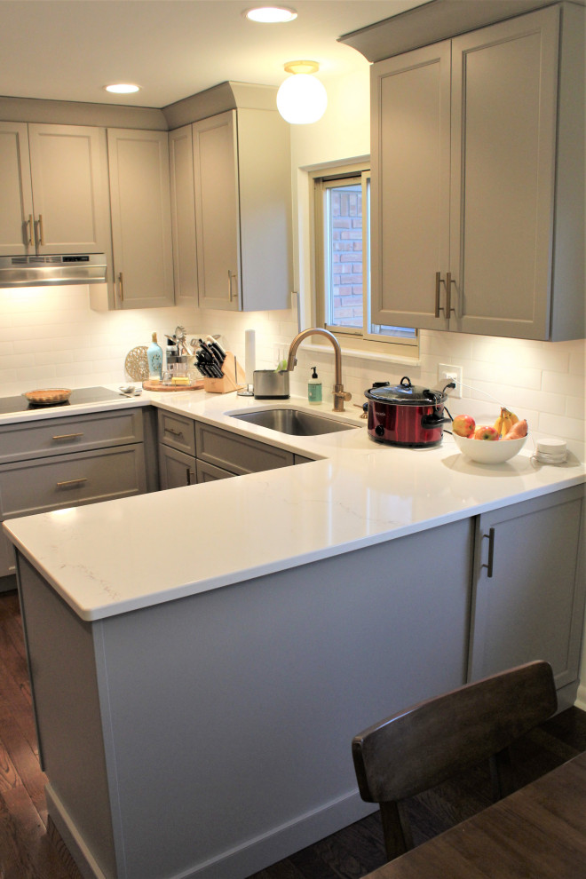 Idéer för ett litet klassiskt grå kök, med luckor med infälld panel, grå skåp, vitt stänkskydd, rostfria vitvaror, en undermonterad diskho, bänkskiva i kvarts, stänkskydd i keramik, mellanmörkt trägolv, en halv köksö och brunt golv