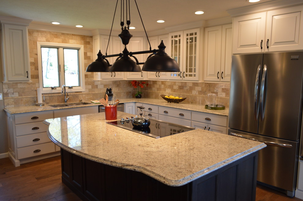 Bild på ett mellanstort vintage l-kök, med en undermonterad diskho, luckor med upphöjd panel, vita skåp, granitbänkskiva, brunt stänkskydd, stänkskydd i stenkakel, rostfria vitvaror, mellanmörkt trägolv, en köksö och brunt golv