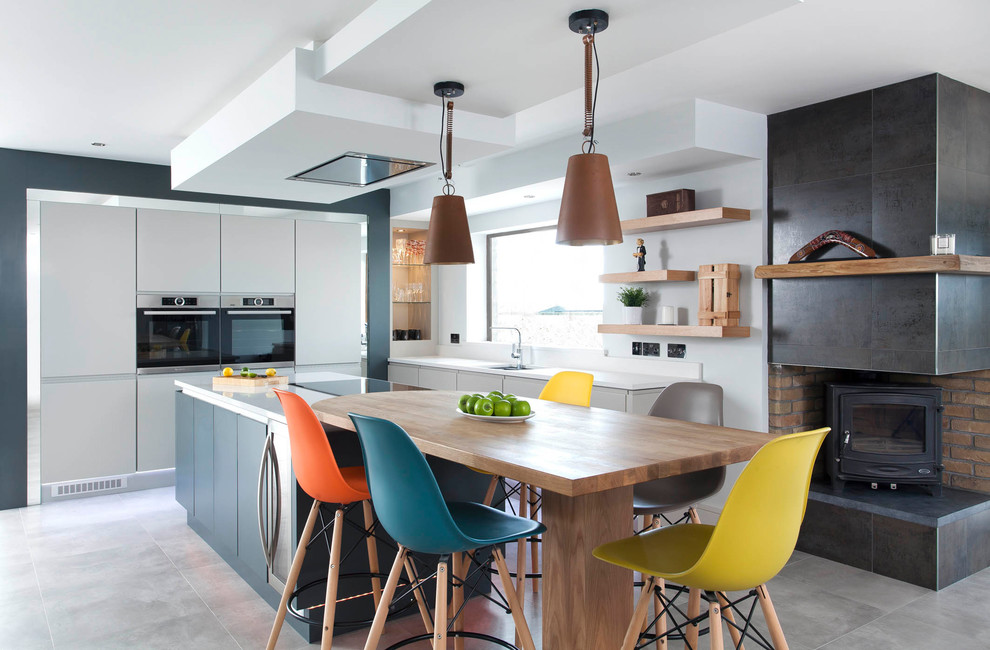 Inspiration for a medium sized contemporary l-shaped kitchen/diner in Other with flat-panel cabinets, grey cabinets, an island, blue splashback, stainless steel appliances and grey floors.