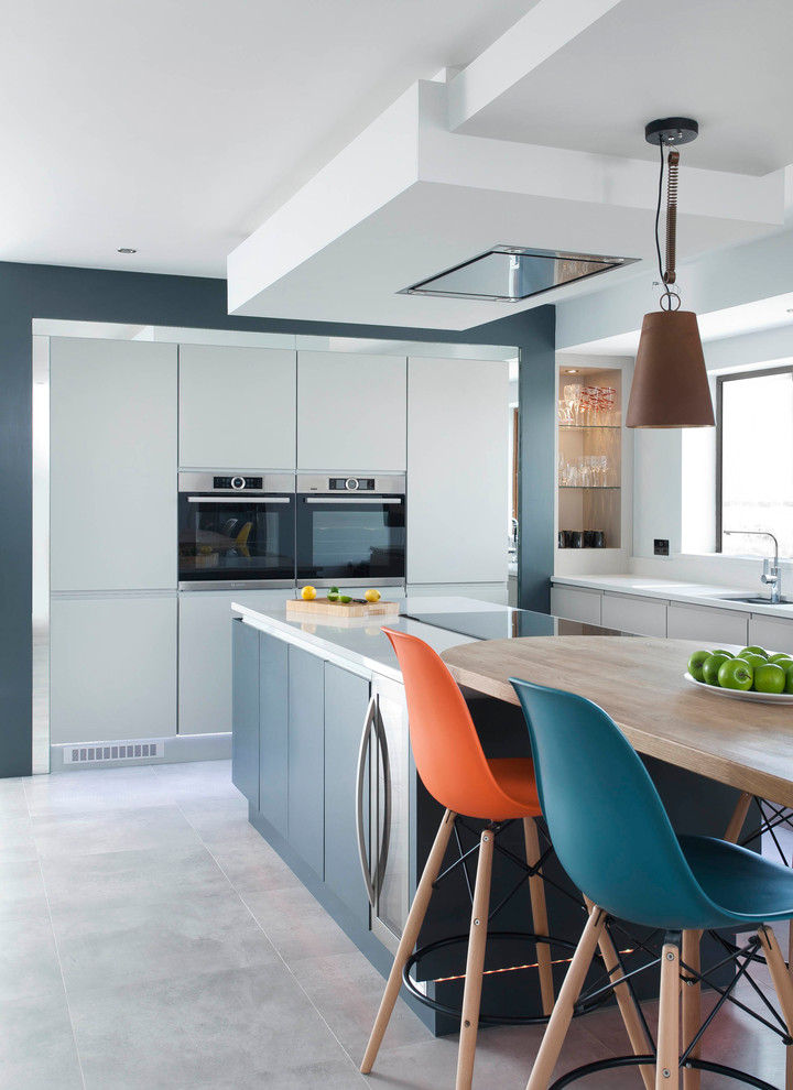 Aménagement d'une cuisine américaine contemporaine avec des portes de placard bleues, un électroménager de couleur, îlot et un sol gris.