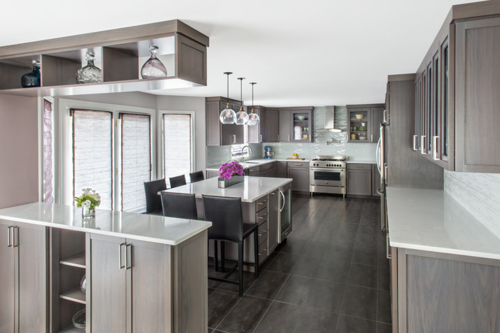 Photo of a large contemporary u-shaped kitchen/diner in New York with a single-bowl sink, shaker cabinets, grey cabinets, engineered stone countertops, white splashback, glass tiled splashback, stainless steel appliances, porcelain flooring and an island.