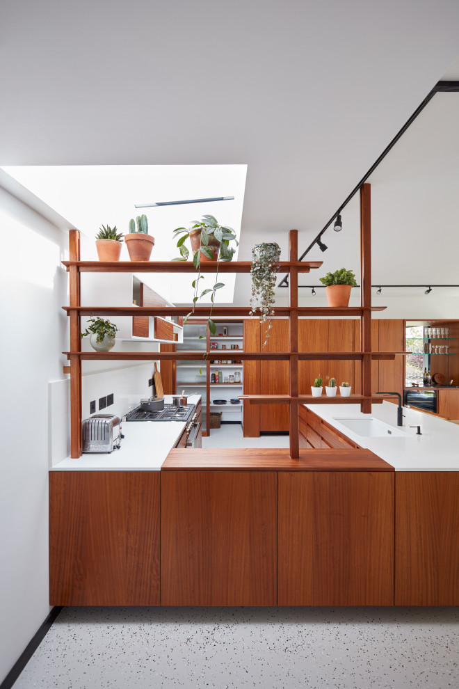 Photo of a large retro u-shaped open plan kitchen in Other with an integrated sink, flat-panel cabinets, medium wood cabinets, quartz worktops, white splashback, engineered quartz splashback, black appliances, an island and white worktops.