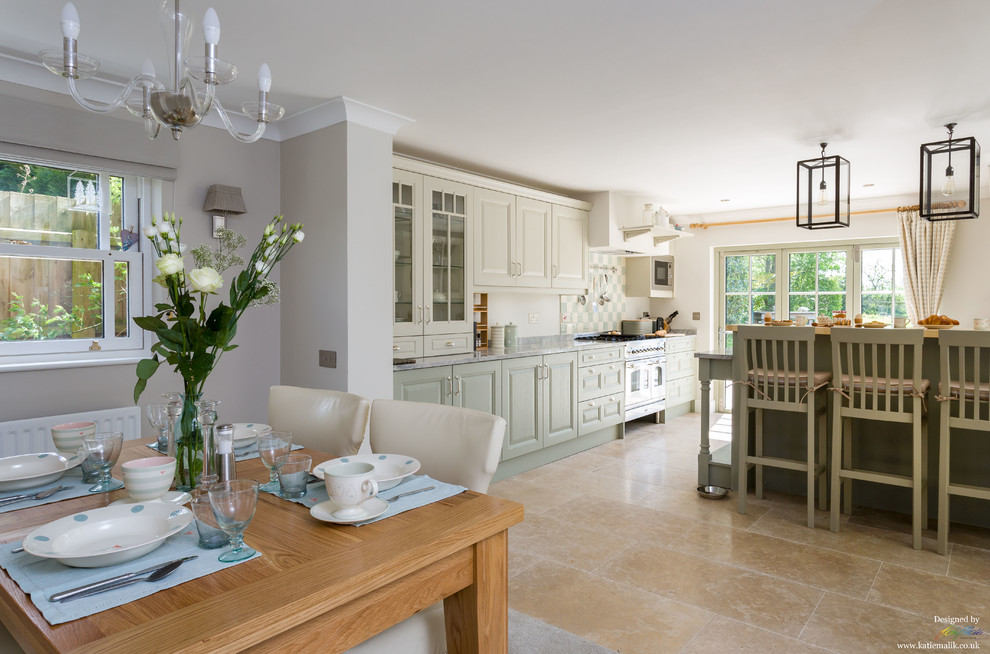 This is an example of a traditional open plan kitchen in Cambridgeshire with a belfast sink, shaker cabinets, green cabinets, marble worktops, ceramic splashback and limestone flooring.