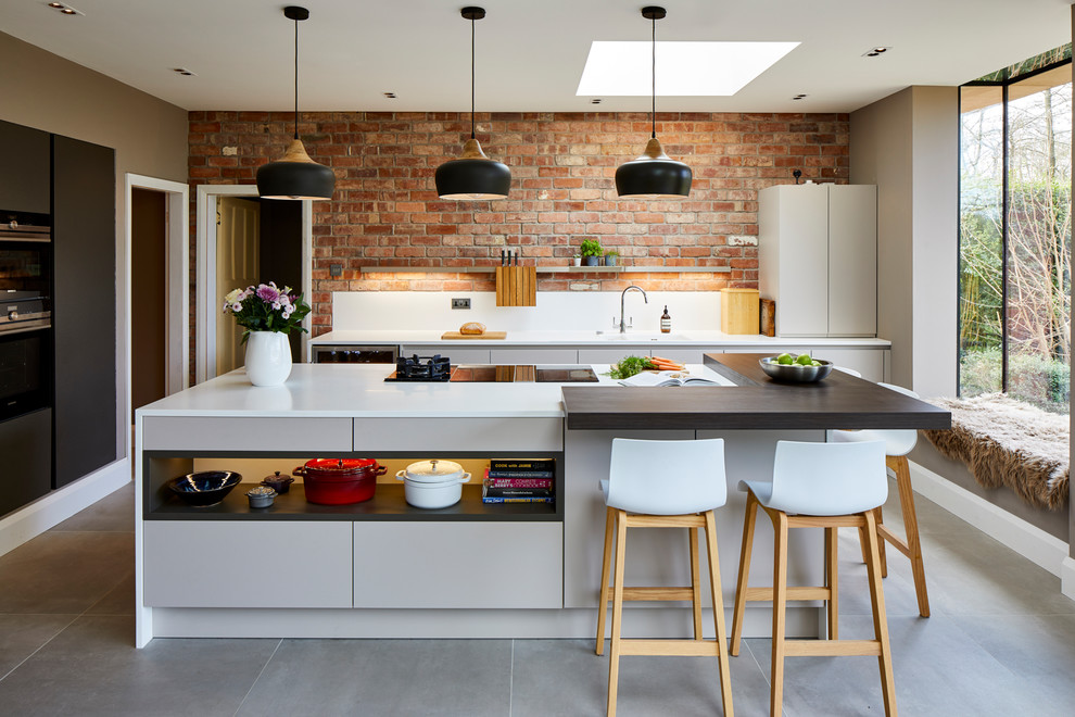 Photo of a contemporary l-shaped kitchen in West Midlands with flat-panel cabinets, grey cabinets, an island, grey floors and white worktops.