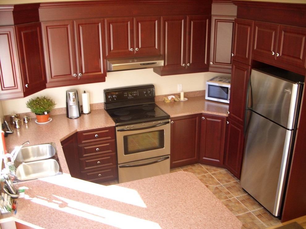 Exempel på ett mellanstort, avskilt klassiskt röd rött u-kök, med en dubbel diskho, rostfria vitvaror, klinkergolv i keramik, luckor med upphöjd panel, röda skåp, granitbänkskiva, en halv köksö och brunt golv