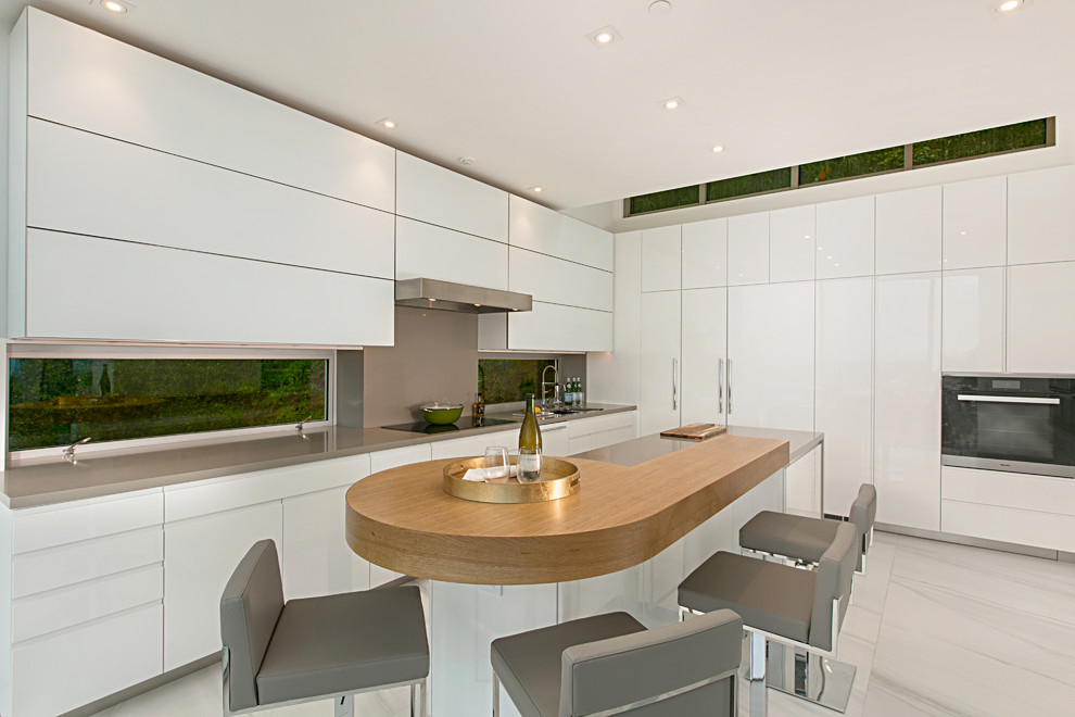 Idee per un cucina con isola centrale minimal con lavello sottopiano, ante lisce, ante bianche, paraspruzzi grigio, pavimento in marmo, pavimento bianco e top grigio