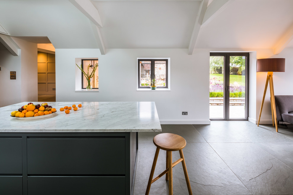 Exempel på ett stort modernt kök, med en integrerad diskho, släta luckor, svarta skåp, bänkskiva i rostfritt stål, vitt stänkskydd, stänkskydd i marmor, rostfria vitvaror, en köksö och grått golv