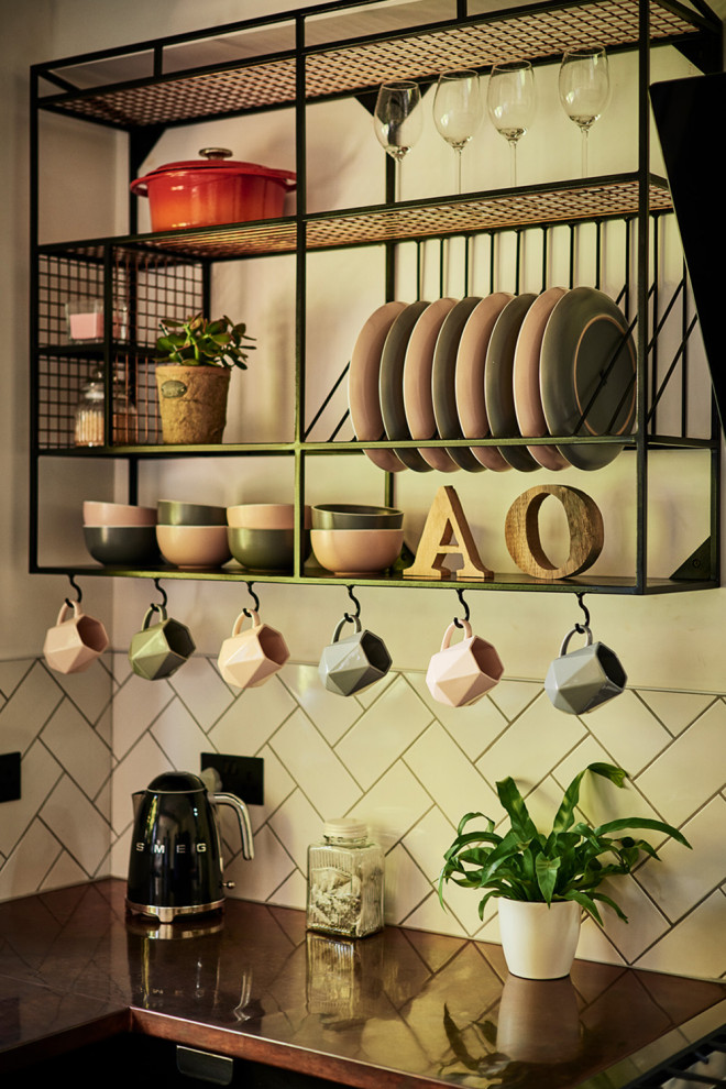 Inspiration for a mid-sized modern u-shaped ceramic tile and multicolored floor eat-in kitchen remodel in Sussex with a drop-in sink, flat-panel cabinets, black cabinets, copper countertops, white backsplash, subway tile backsplash, black appliances and a peninsula