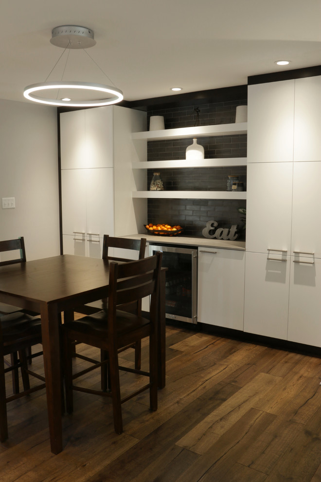 Photo of a medium sized industrial galley kitchen/diner in Other with white cabinets, grey splashback, metro tiled splashback, stainless steel appliances, light hardwood flooring, an island and beige floors.
