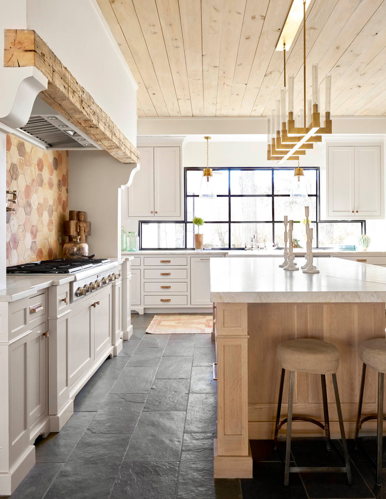 Inspiration for a large farmhouse l-shaped black floor and slate floor kitchen remodel in Dallas with shaker cabinets, white cabinets, an island, multicolored backsplash, white countertops, a farmhouse sink, quartz countertops, stainless steel appliances and window backsplash