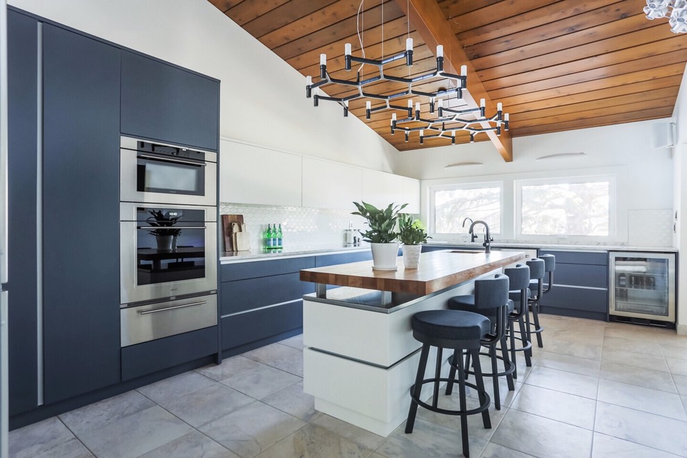 Idee per una cucina moderna di medie dimensioni con ante lisce, ante blu, top in legno, paraspruzzi bianco, elettrodomestici in acciaio inossidabile, pavimento con piastrelle in ceramica e pavimento grigio
