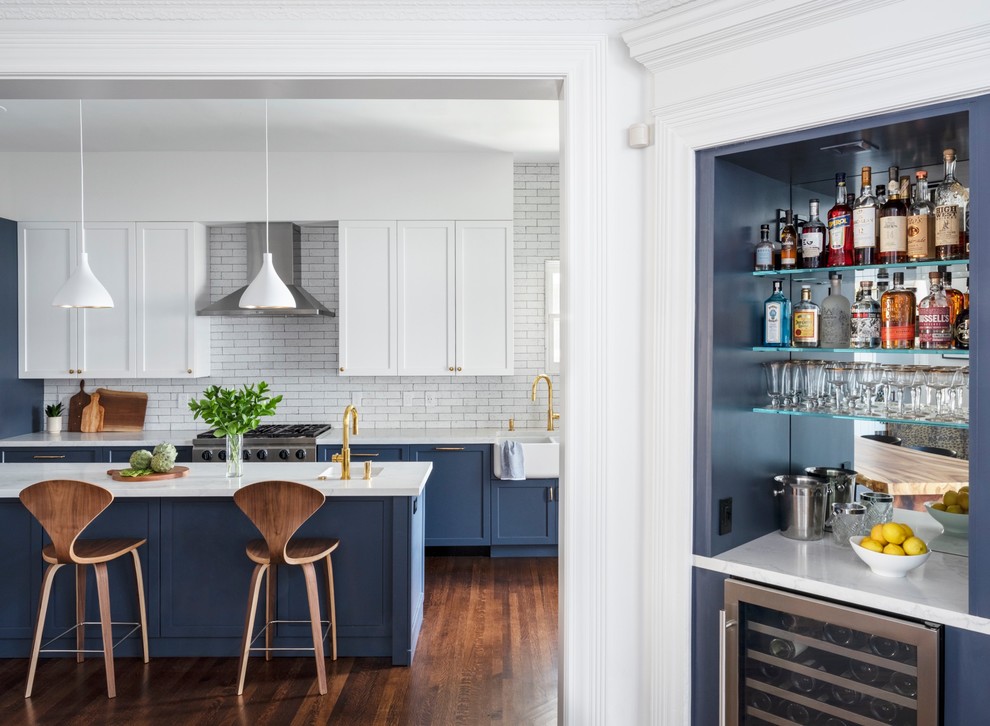Inspiration for a transitional medium tone wood floor and brown floor kitchen remodel in San Francisco with a farmhouse sink, white cabinets, quartz countertops, white backsplash, stainless steel appliances, an island and white countertops
