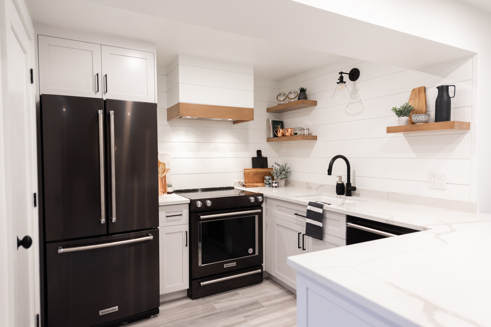 Inspiration for a small cottage l-shaped laminate floor and gray floor open concept kitchen remodel in Montreal with a single-bowl sink, shaker cabinets, white cabinets, quartzite countertops, white backsplash, wood backsplash, black appliances, no island and white countertops