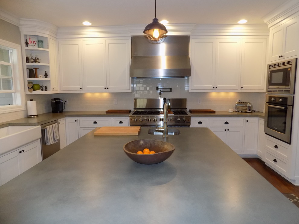 Eat-in kitchen - large contemporary u-shaped medium tone wood floor eat-in kitchen idea in Columbus with a farmhouse sink, recessed-panel cabinets, white cabinets, concrete countertops, white backsplash, ceramic backsplash, stainless steel appliances and an island