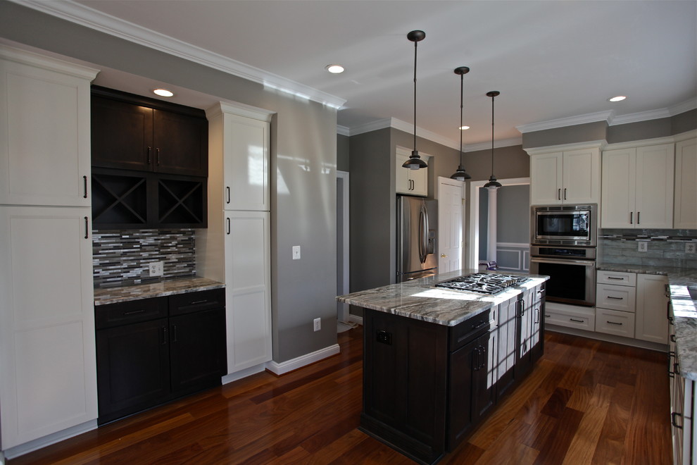 Inspiration for a mid-sized transitional l-shaped medium tone wood floor eat-in kitchen remodel in DC Metro with an undermount sink, shaker cabinets, white cabinets, granite countertops, stainless steel appliances, an island, multicolored backsplash and matchstick tile backsplash