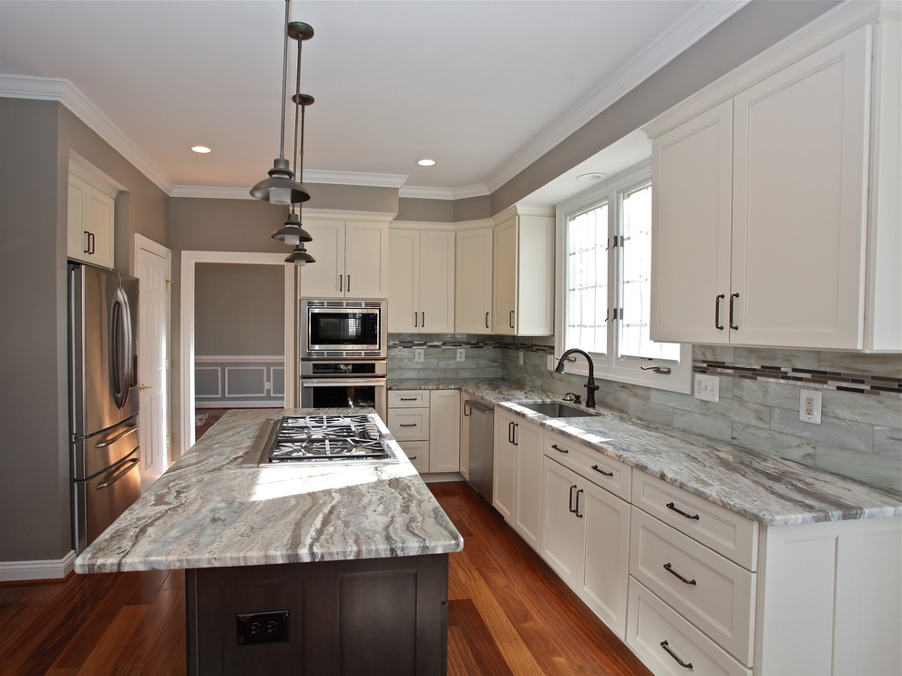 Inspiration for a mid-sized transitional l-shaped medium tone wood floor eat-in kitchen remodel in DC Metro with an undermount sink, shaker cabinets, white cabinets, granite countertops, glass tile backsplash, stainless steel appliances, an island and multicolored backsplash