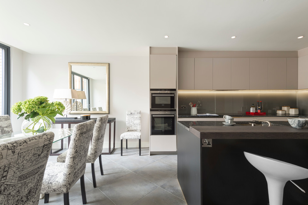 Trendy eat-in kitchen photo in London with an undermount sink, flat-panel cabinets, gray backsplash and an island