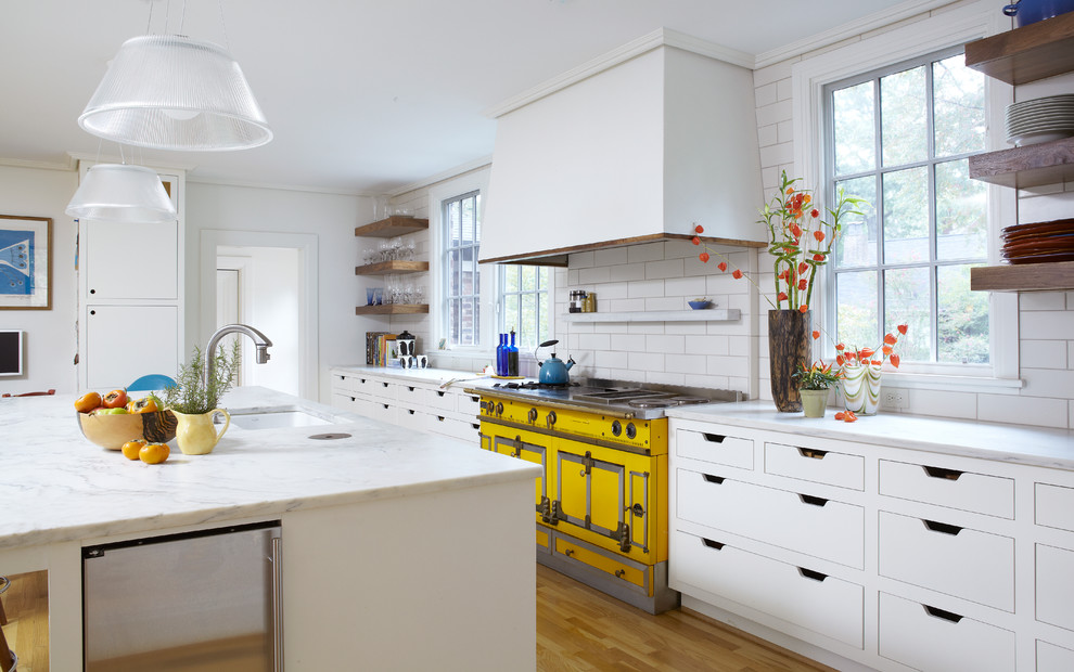 Cette image montre une cuisine design avec un placard à porte plane, des portes de placard blanches, une crédence blanche, une crédence en carrelage métro et un électroménager de couleur.